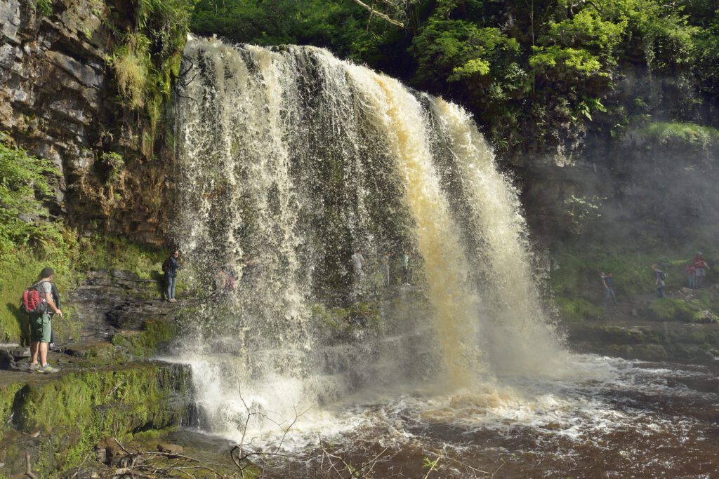 Walking behind Sgwd Yr Eira waterfall; Afon Hepste River in Brecon