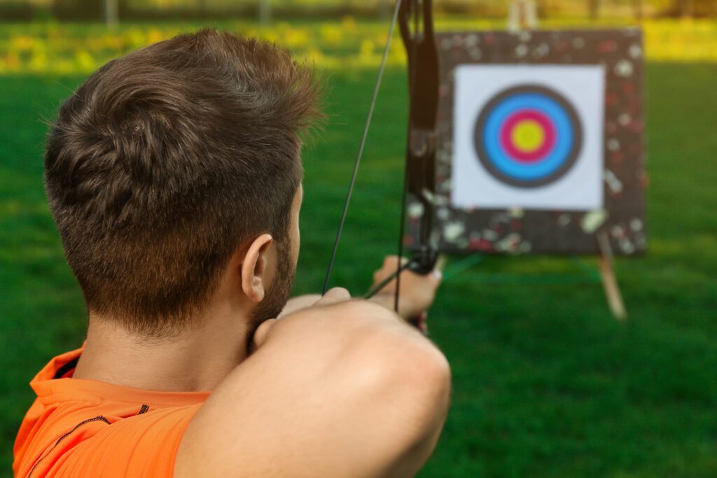 Man,With,Bow,And,Arrow,Aiming,At,Archery,Target,In
